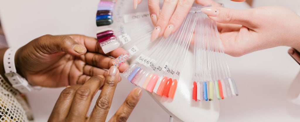 Nail tech reviews nail color options with client